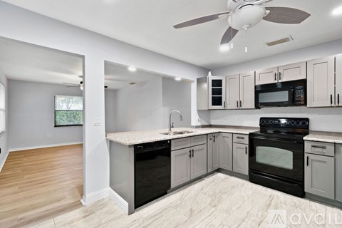 A modern kitchen with black appliances and white cabinets.