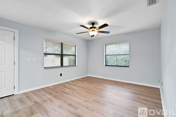 A room with a ceiling fan and two windows.
