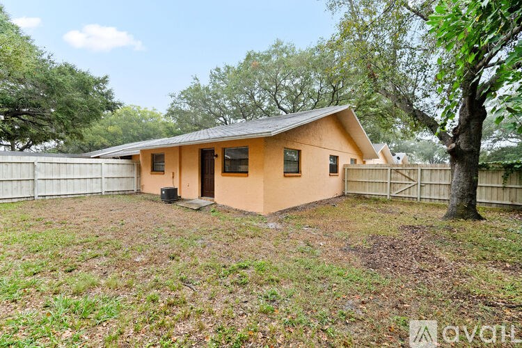 A small house with a brown roof and a white fence in the yard.