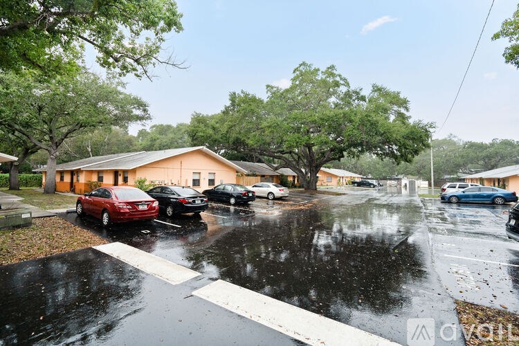 A wet street with cars parked on the side.