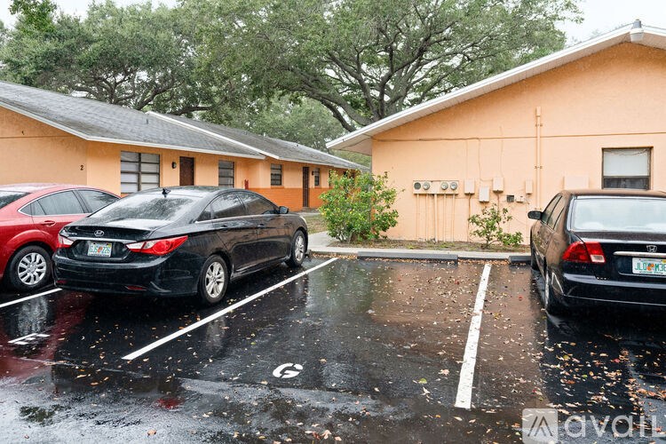 Two cars are parked in a wet parking lot.