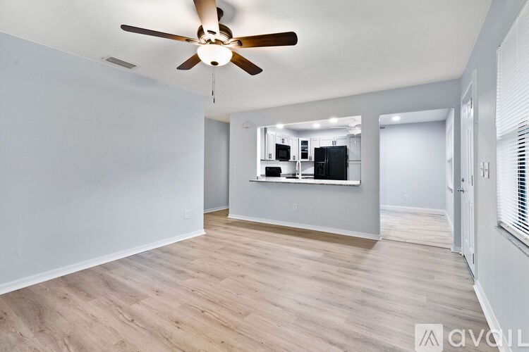 A room with a ceiling fan and wooden flooring.
