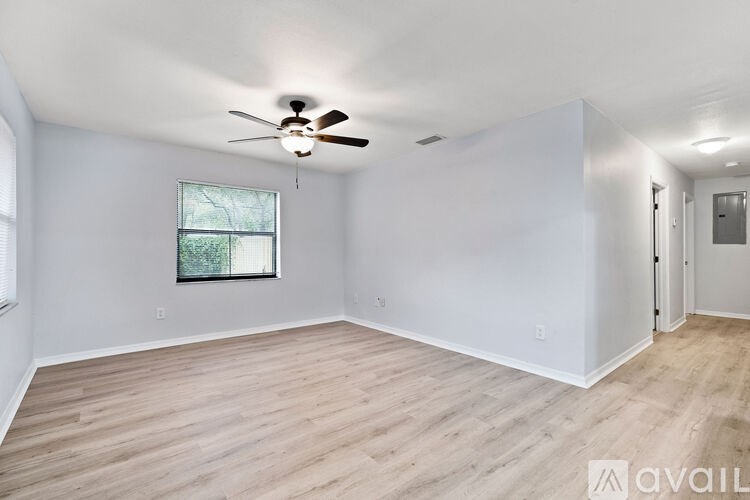 A spacious room with a ceiling fan and wooden flooring.