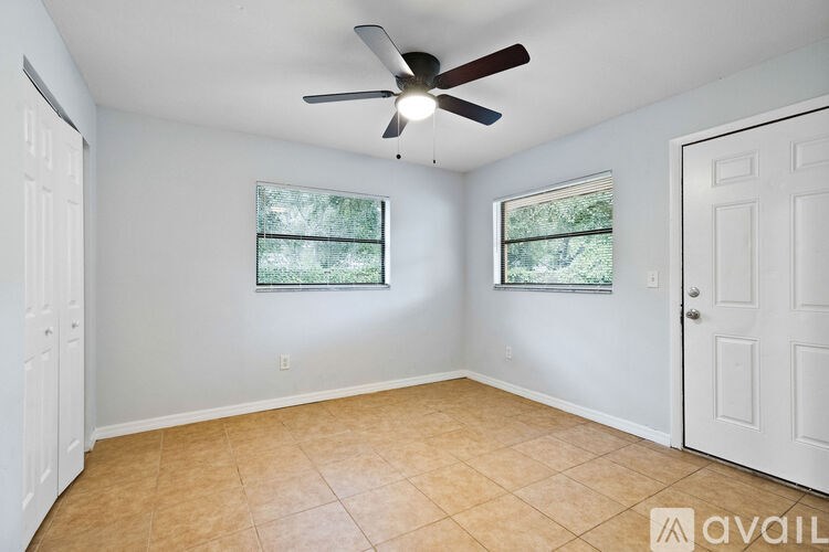 A room with a ceiling fan and two windows.