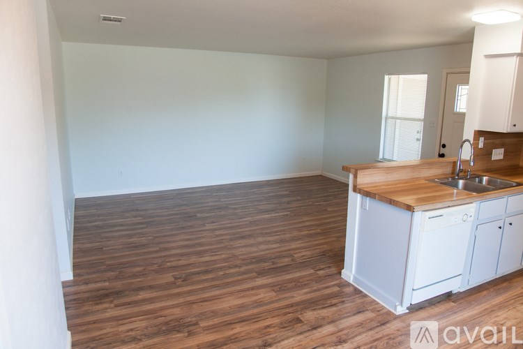 A kitchen area with wooden flooring and white cabinets.
