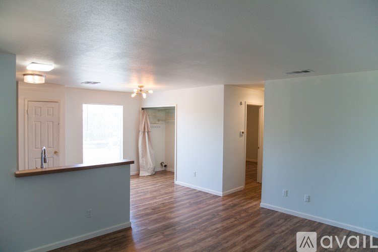 A room with wooden floors and white walls, with a window and a door visible.