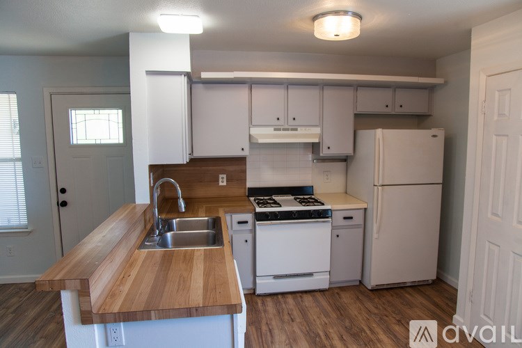 A kitchen with a wooden countertop and white appliances.