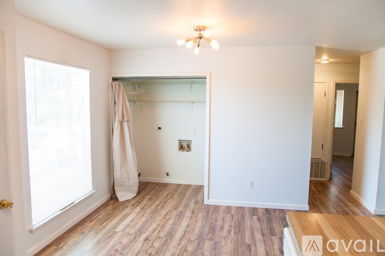 A room with a wooden floor and a window with blinds.