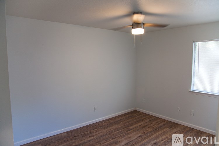 A room with a ceiling fan and wooden flooring.