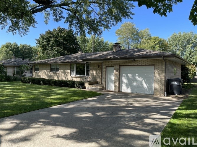 A house with a driveway and a tree in front of it.