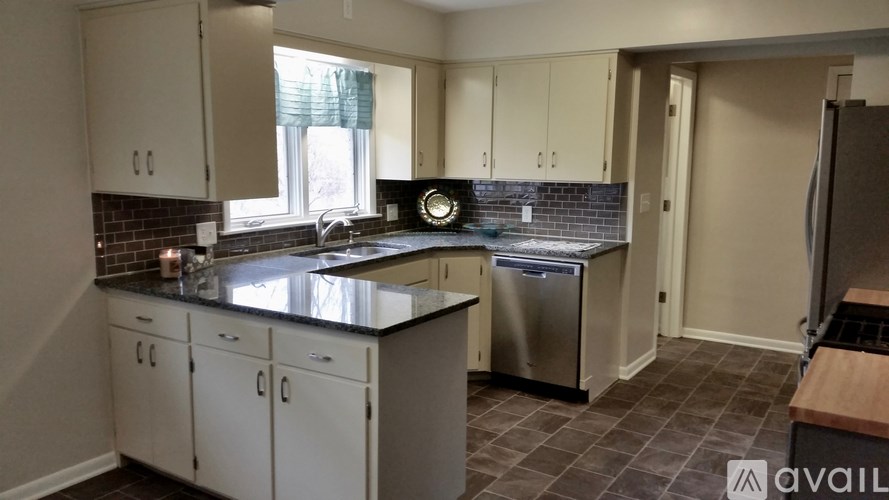 A kitchen with white cabinets and a black countertop.