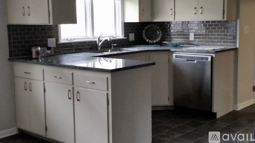 A kitchen with white cabinets and a black countertop.