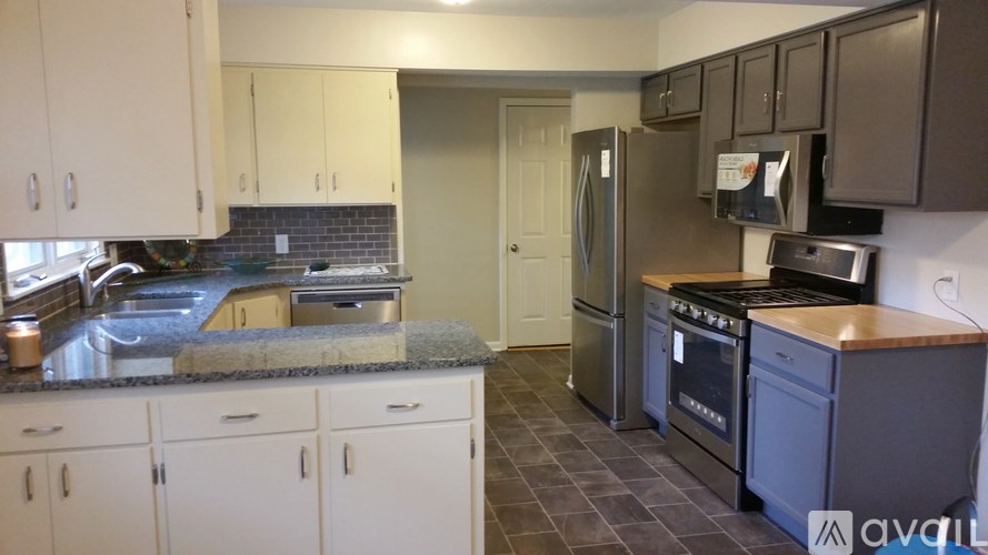 A kitchen with white cabinets and a black fridge.