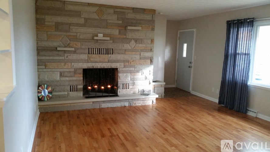 A room with a stone fireplace and wooden floors.