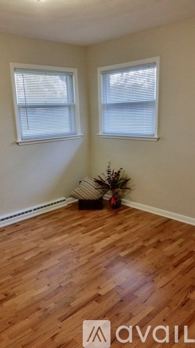 A room with wooden floors and two windows.