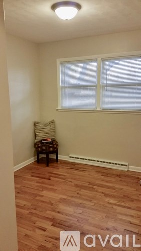 A room with a wooden floor and a window with blinds.