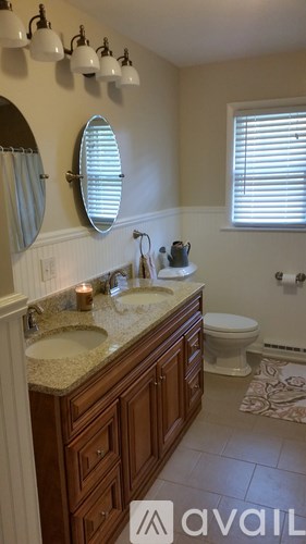 A bathroom with a round mirror, a sink, and a toilet.