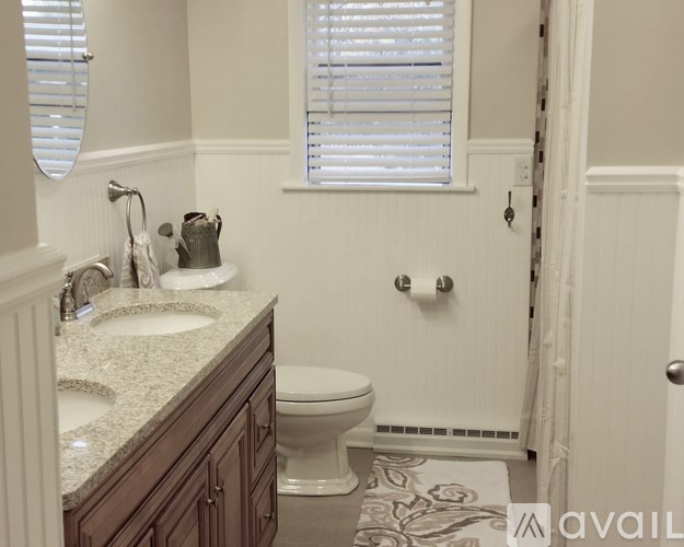 A bathroom with a toilet, sink, and window.