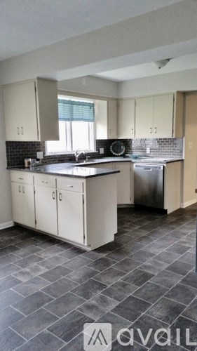 A kitchen with a black counter top and white cabinets.