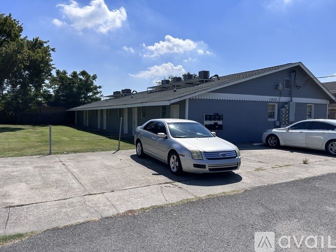 A silver car is parked in a driveway in front of a grey house.