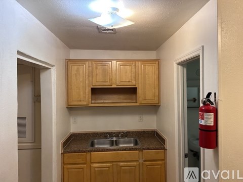 A kitchen with wooden cabinets and a red fire extinguisher on the wall.