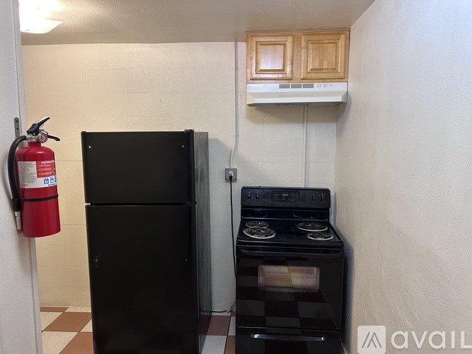 A black refrigerator and stove in a small kitchen.
