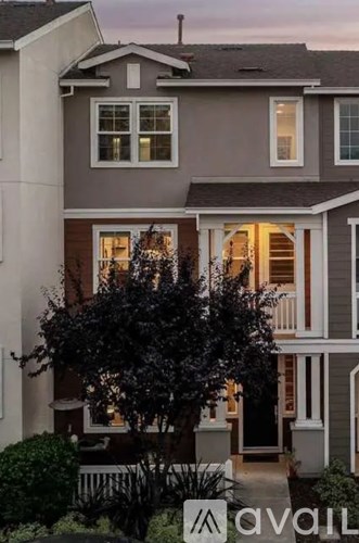 A house with a front yard and a tree in front of it.