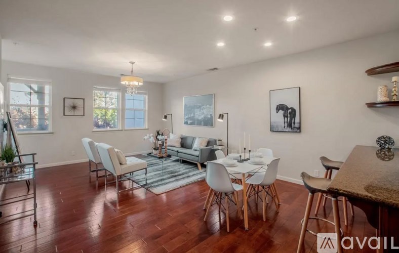 A modern dining room with a wooden floor and white chairs.