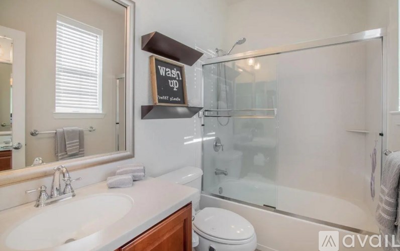 A bathroom with a white sink, toilet, and a glass shower stall.