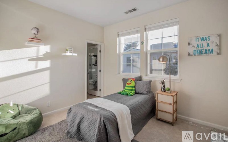 A bedroom with a bed, a green bean bag chair, and a sign on the wall that says "It was all a dream".