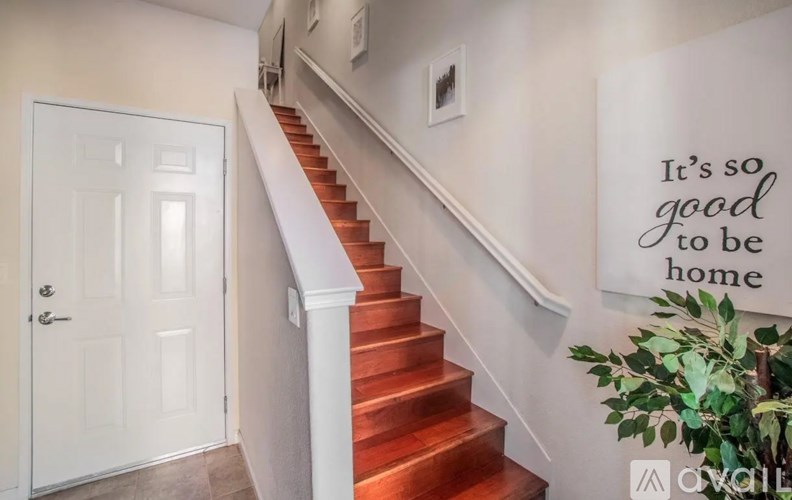 A staircase with a quote on the wall that says "It's so good to be home".