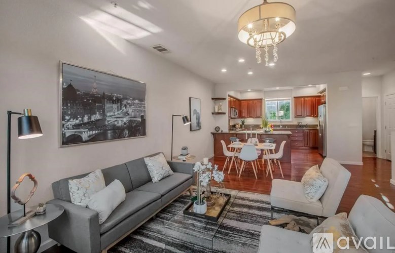 A living room with a grey couch, a coffee table, and a chandelier.