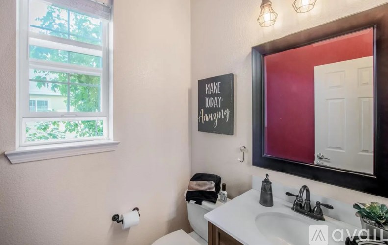 A bathroom with a sink, mirror, and a sign on the wall.