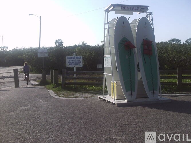 A rental kiosk with two surfboards is set up in a parking lot.