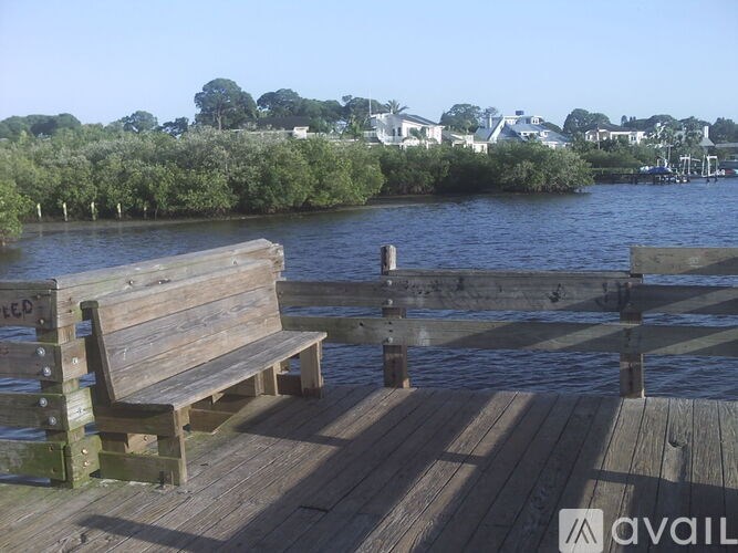 A wooden bench sits on a dock by the water.