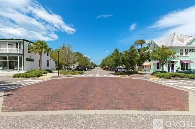 A street view with a red brick road in the foreground and buildings on either side.