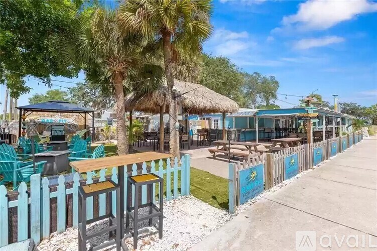 A row of blue chairs and tables are set up outside on a sunny day.