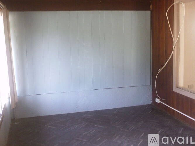 A room with a wooden wall and a window with blinds.