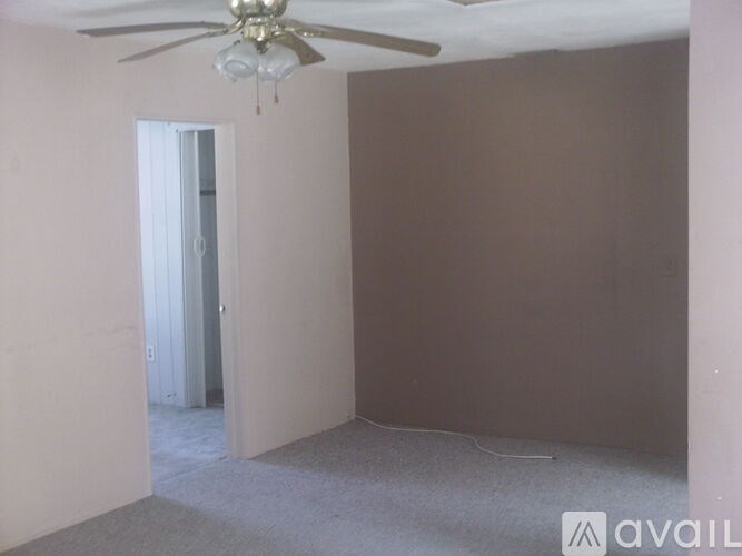 A room with a ceiling fan and a doorway leading to another room.