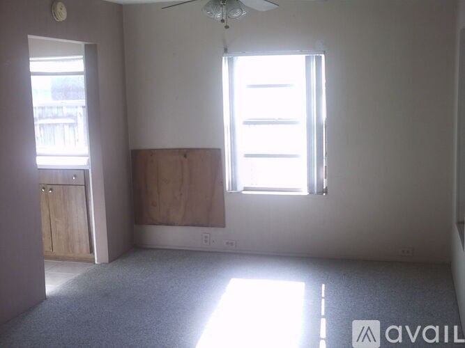A room with a ceiling fan and two windows.