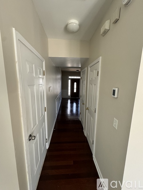 A long hallway with white doors and a light on the ceiling.