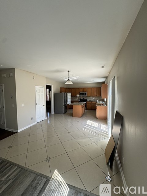 A spacious living room with a kitchen in the background.
