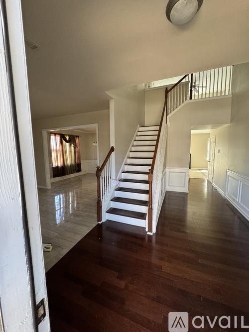 A wooden staircase with white railings leads to a second floor.