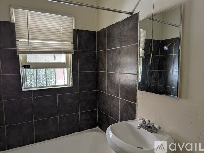 A bathroom with a white sink and a window with blinds.