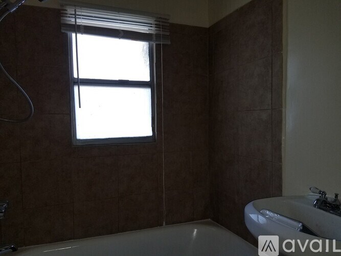 A bathroom with brown tiles and a white tub.