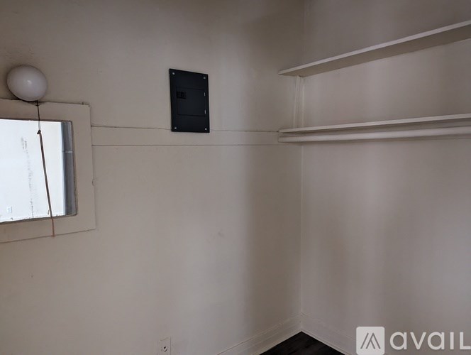 A room with a window, a white lamp, and a black box on the wall.