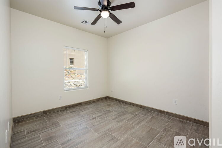 A room with a ceiling fan and a window showing a view of a building outside.