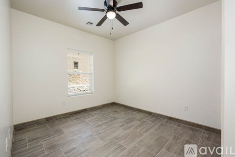 A room with a ceiling fan and a window showing a view of a building outside.