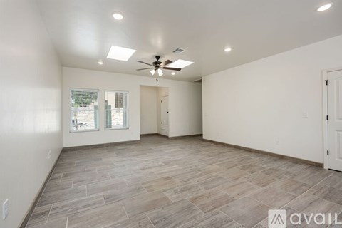 A spacious room with a ceiling fan and lighting fixtures.