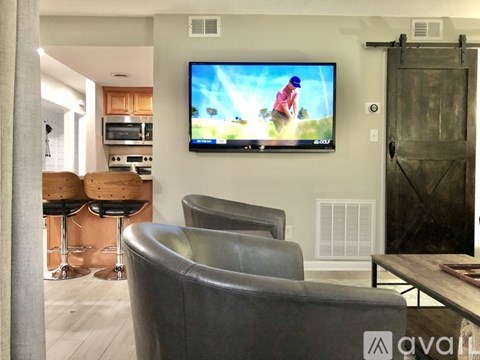 A living room with a television on the wall and a chair in the foreground.